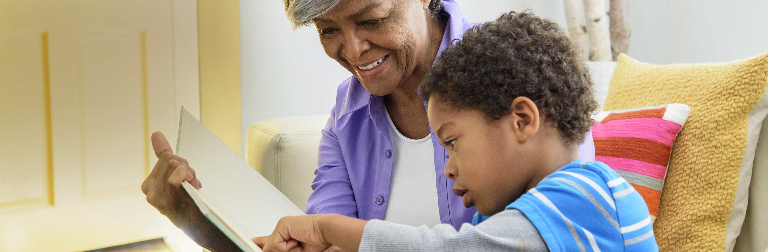 Woman and boy reading book together on couch