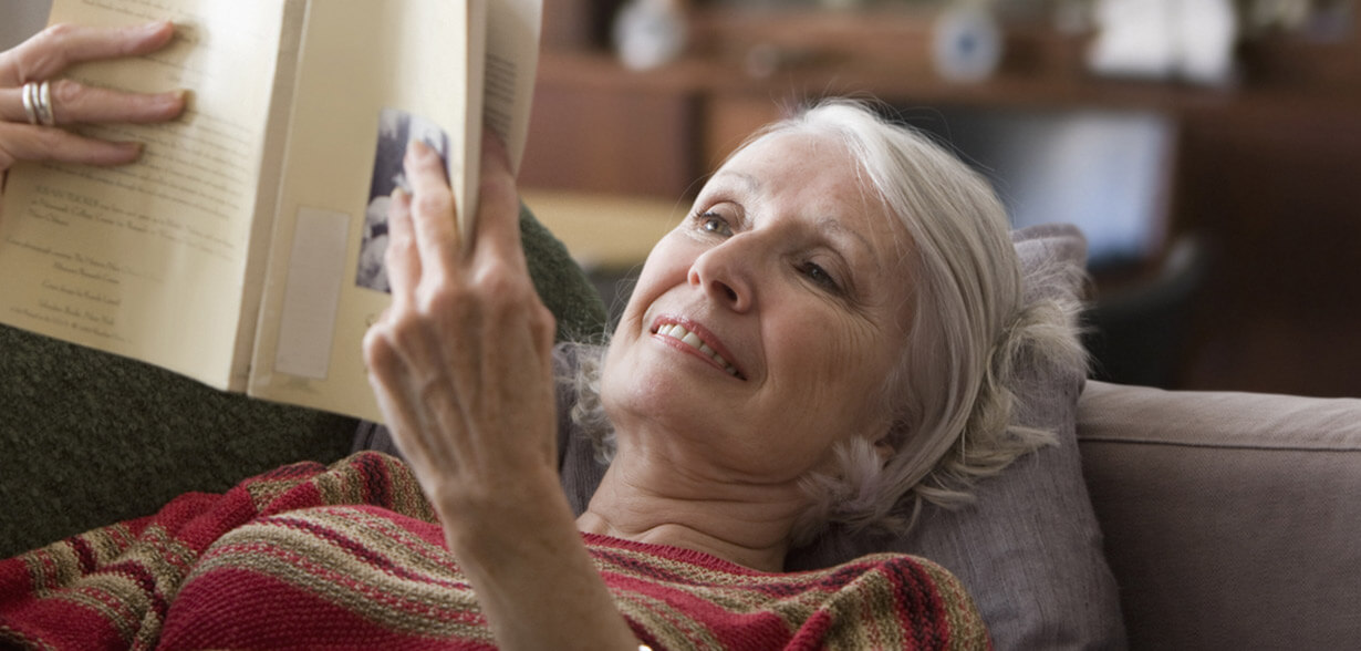 Woman laying on couch reading book