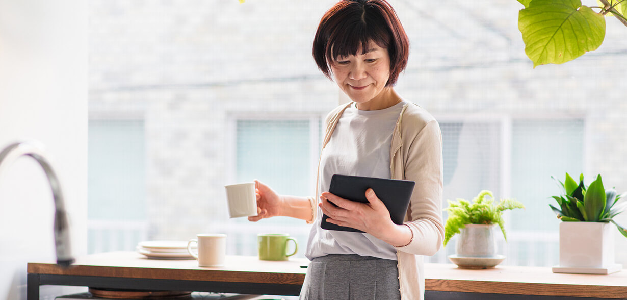 Woman holding coffee mug and tablet