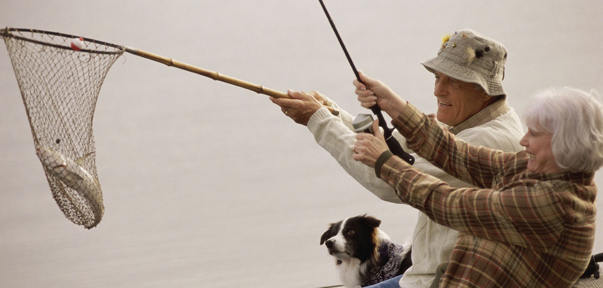 Elderly couple fishing with a net and fishing rod